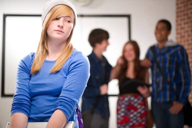 Young woman excluded from a group of peers who are laughing