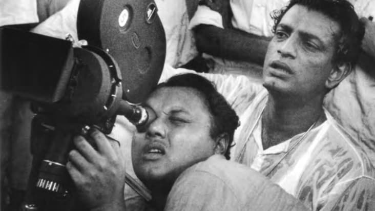 Satyajit Ray, sitting behind the camera operator, on set